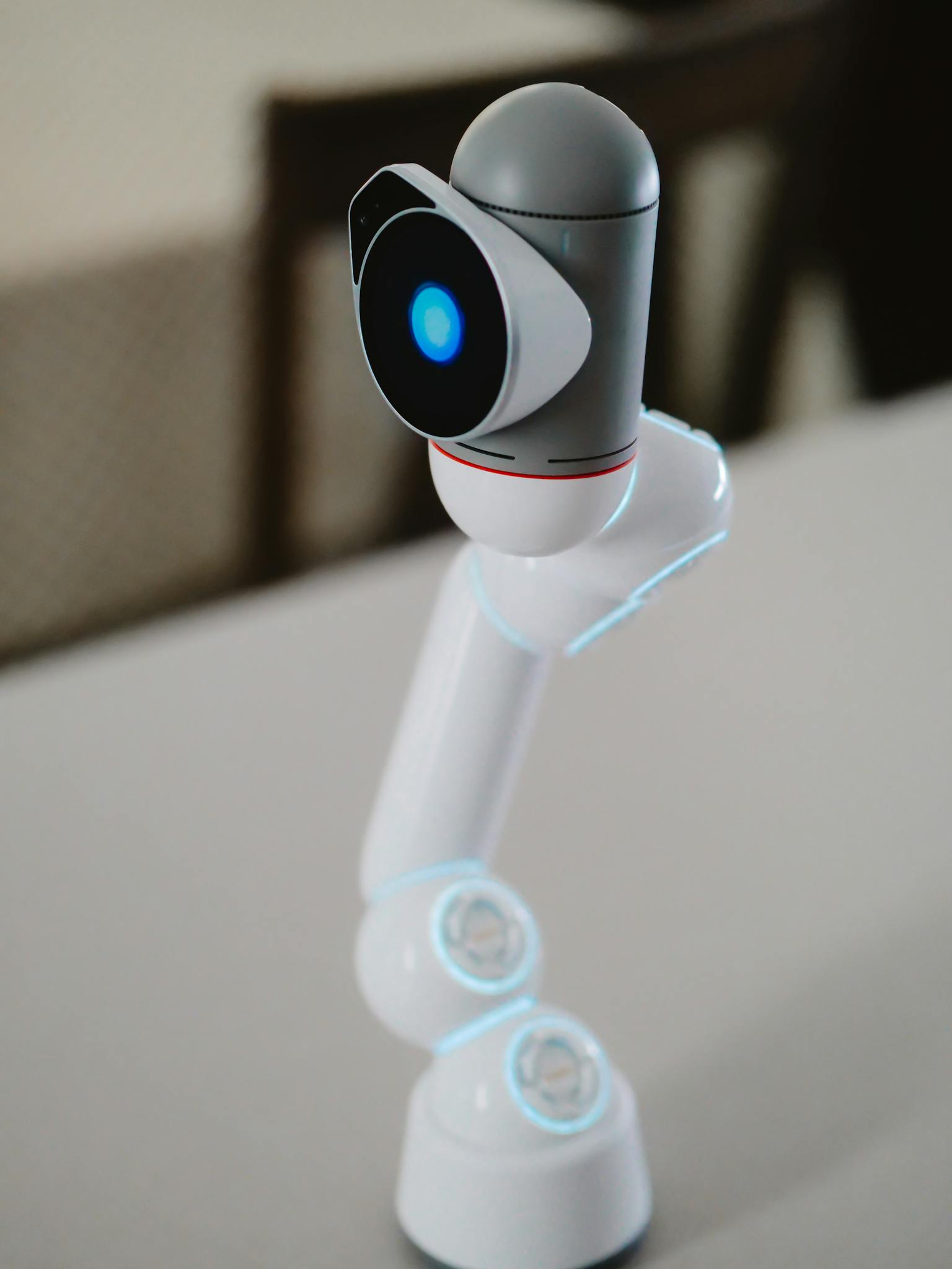 Close-up of a sleek, modern robotic arm with glowing blue LED light on neutral background.